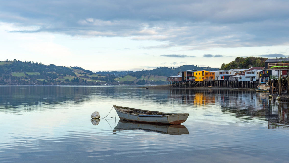 A lone fishing boat by the palafitos stilt houses in Castro, Chiloe Island, Chile.