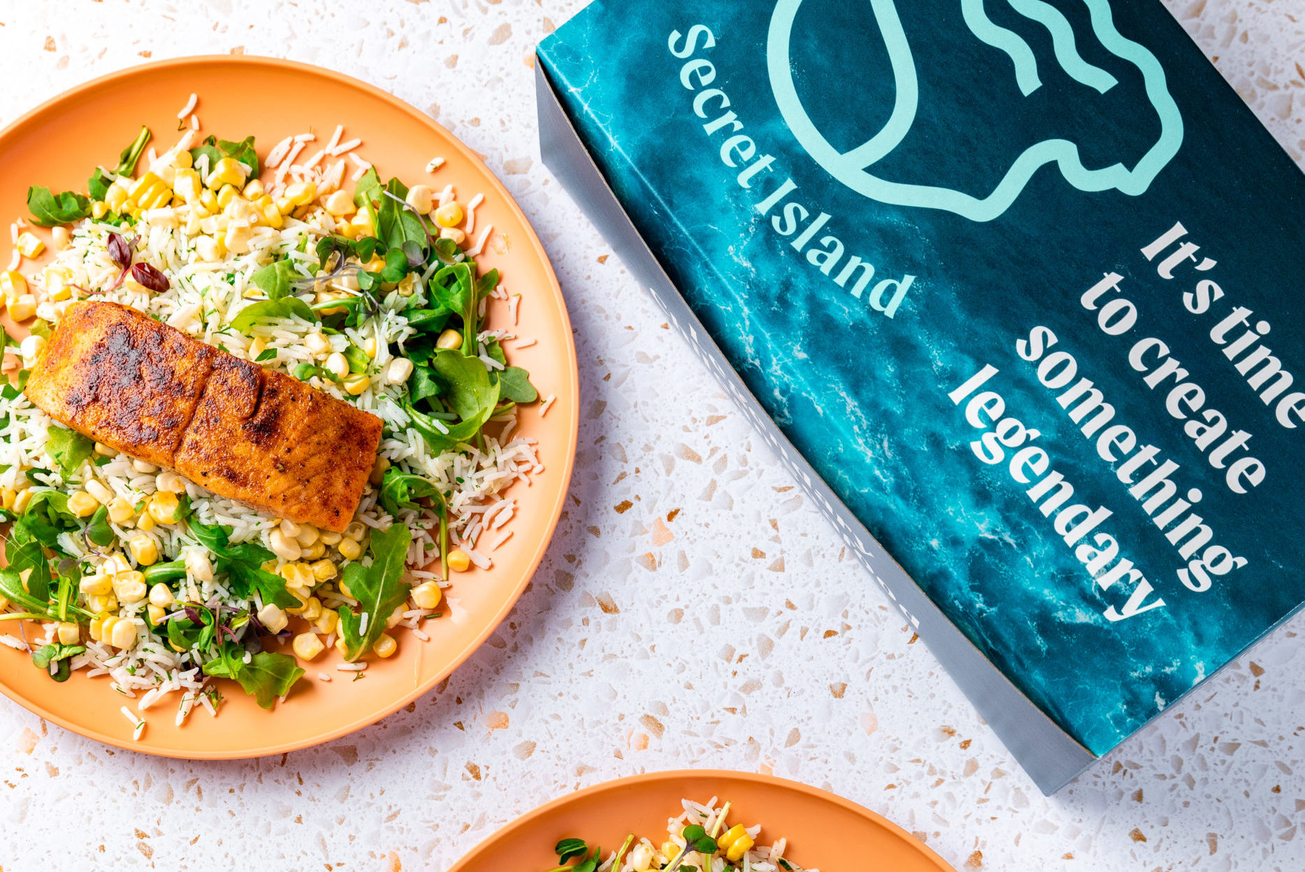 Spiced salmon on bed of greens and basmati rice. Blue box with the words "It's time to create something legendary" sits beside the dish.